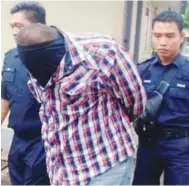  ??  ?? Hazrin covers his face with his T-shirt as he is led into court yesterday.