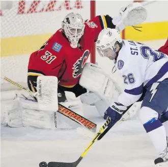  ?? Ted Rhodes/calgary Herald ?? Tampa Bay Lightning captain Martin St. Louis tries to corral the puck in front of Calgary goalie Karri Ramo Friday night as the Flames were shut out at the Saddledome. They’re on the road Monday.