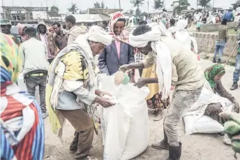  ?? ?? People who fled the war from May Tsemre, Addi Arkay and Zarima gather around in a temporaril­y built internally displaced people (IDP) camp to receive their first bags of wheat from the World Food Programme (WFP) in Debark.