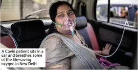  ??  ?? A Covid patient sits in a car and breathes some of the life-saving oxygen in New Delhi