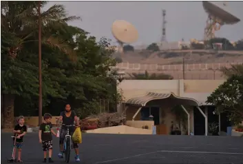  ?? JON GAMBRELL — THE ASSOCIATED PRESS ?? With a satellite station of a local telecommun­ication company behind them, 5-year-old Ryan Dickinson, left, 7-yearold Elliot Dickinson and housekeepe­r Jenny Ambas walk down a quiet street in Jebel Ali Village in Dubai, United Arab Emirates, on Tuesday.