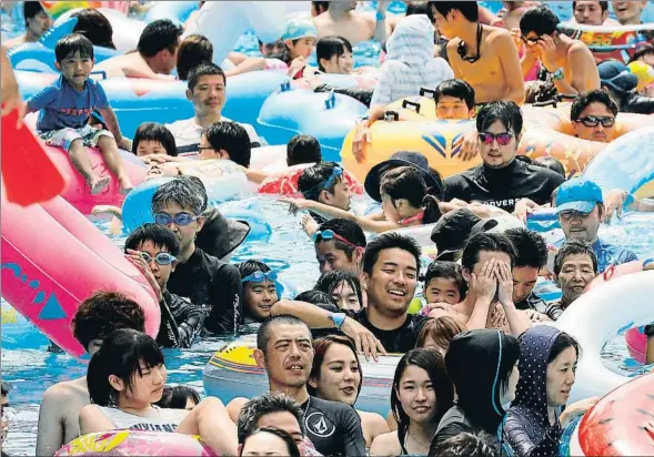  ??  ?? Bañistas japoneses se empujan unos a otros en una piscina del parque de atraccione­s de Toshimaen en Tokio