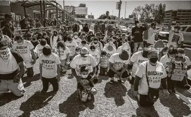  ?? Zuma Press / Tribune News Service ?? A group of migrants wearing T-shirts that read, “Biden, please let us in,” kneel and pray Tuesday at the border crossing in San Ysidro, Mexico.