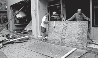 ?? Associated Press Chris Seward, The ?? Jay Manning, left, and Shannon Corr clean up the storefront of the Surf, Wind and Fire store on Sept. 15. The business in New Bern, N.C., was damaged by the Tropical Storm Florence.