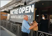  ?? AL SEIB/LOS ANGELES TIMES ?? Greg Thomas picks up his lunch from Samantha Madec at Lure Fish House on South California Street in downtown Ventura on Wednesday as Ventura County modified its stay-at-home order to permit some businesses to reopen.
