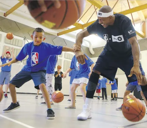  ?? MICHELLE BERG ?? Garrett Buffalo practises dribbling with former Toronto Raptor Jerome Williams at Charles Red Hawk Elementary School on Whitecap First Nation as part of the BMO and NBA’s Courts Across Canada project on Wednesday.