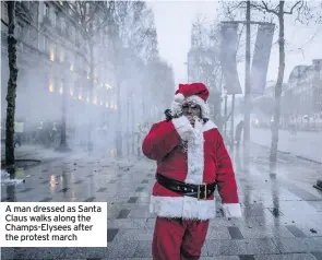  ??  ?? A man dressed as Santa Claus walks along the Champs-Elysees after the protest march