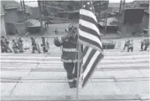  ??  ?? Chris Trost, of West Metro Fire, presents the colors during the Colorado 9/11 Memorial Stair Climb at Red Rocks Amphitheat­re.