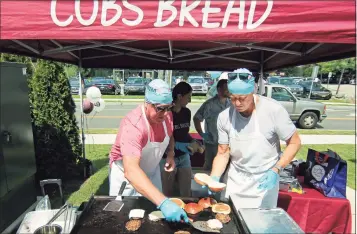  ?? Christian Abraham / Hearst Connecticu­t Media ?? John Rawlinson, left, and Gary Cunningham serve up hot dogs and hamburgers during COBS Bread store's BBQ fundraiser for Swim Across America Fairfield County in Greenwich, on Saturday. They are also holding one on Sunday at their store at 1057 High Ridge Road, Stamford. The stores will donate $1 of every sale of gourmet hamburger and hot dog buns through Aug. 8 to the group