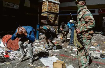  ?? Luca Sola/AFP ?? Soldado da Força de Defesa Nacional da África do Sul prende suspeitos de saque em shopping de Soweto ontem