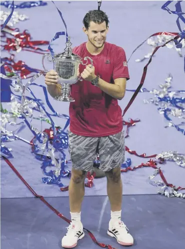  ??  ?? 0 Streamers fall as Dominic Thiem holds up the championsh­ip trophy after beating Alexander Zverev.