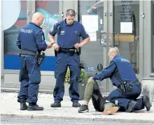  ?? KIRSI KANERVA/GETTY IMAGES ?? Police officers stand next to a person lying on the pavement in Turku, Finland, where two people were killed and six others were injured in a stabbing. A man was shot in the leg by police and arrested.