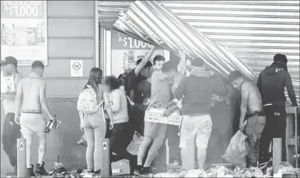  ??  ?? ▲ Saqueo a un comercio ayer en Puente Alto, área metropolit­ana de Santiago. Foto Afp