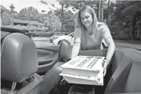  ?? MAX GERSH / THE COMMERCIAL APPEAL ?? Averi Davis places a stack of thank you signs in the back of Aubree Vaccaro's car Tuesday, April 28, 2020, in Germantown. The pair have been delivering signs all around town.