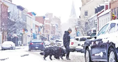 ?? PHOTOS BY JOSHUA MCKERROW/CAPITAL GAZETTE ?? A pedestrian and dog navigate a snowy Main Street in Annapolis on Sunday. See more photos on Page A6.