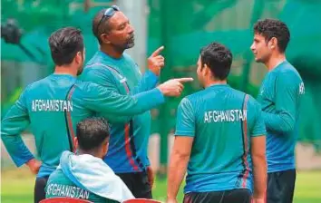  ?? AFP ?? ■ Afghanista­n coach Phil Simmons (second from left) with cricketers during a practice session in Bengaluru yesterday. India and Afghanista­n play a one off Test in Bengaluru from tomorrow.