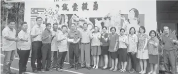  ??  ?? Sim (sixth left) handing over a greeting card and cheque to SJK Chung Hua Sejijak headmaster as others look on.