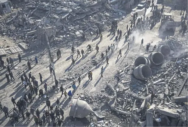  ?? ?? Palestinia­ns take in the destructio­n after an Israeli strike on a residentia­l area left the al-farouq Mosque destroyed, its concrete domes tumbled around, in the Gaza city of Rafah