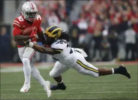  ?? JAY LAPRETE — THE ASSOCIATED PRESS ?? Michigan linebacker Devin Gil, right, tackles Ohio State running back Demario McCall (North Ridgeville) during the first half Nov. 24 in Columbus.