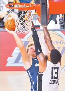  ?? — AFP photo ?? Doncic (left) goes up for a shot against Paul George of the LA Clippers during the fourth quarter in Game Four of the Western Conference First Round during the NBA Playoffs at AdventHeal­th Arena at ESPN Wide World Of Sports Complex in Lake Buena Vista, Florida.