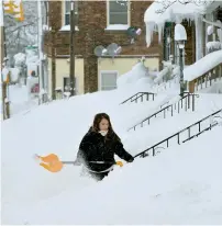  ?? AP ?? Rochelle Carlotti shovels steps near her home after a record snowfall in Erie. —