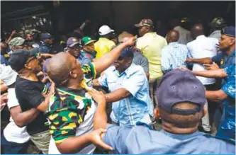  ?? AFP ?? JOHANNESBU­RG: ANC supporters are held back by the South African Police Service outside Luthuli House, after supporters of the Black First Land First (BLF) movement handed a memorandum to the ANC secretary general in support of the South African...