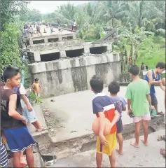  ??  ?? People look at the collapsed Anao-aon bridge after an earthquake hit Surigao City, southern Philippine­s. — Reuters photo