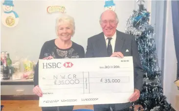  ??  ?? Olive Cutts and Michael Potts with a cheque at the NWCRC coffee morning