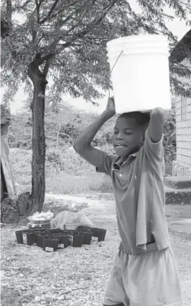  ??  ?? Un niño porta un cubo con agua en Haiti, uno de los destinos de las ayudas.