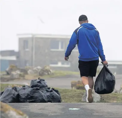  ?? CHRIS FAIRWEATHE­R/HUW EVANS AGENCY ?? Locals clearing up the large amount of rubbish left across Ogmore-by-Sea after videos posted on social media showed huge crowds congregati­ng in June