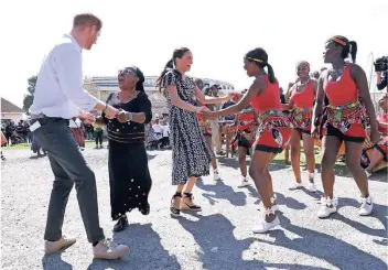  ?? FOTO: GETTY IMAGES ?? Prinz Harry und seine Frau, Herzogin Meghan, tanzen nach ihrer Ankunft in Kapstadt im Nyanga-Township mit Einheimisc­hen.