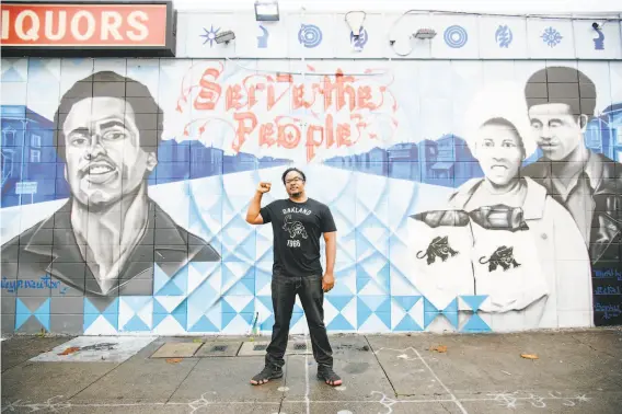  ?? Michael Short / Special to The Chronicle ?? Artist Senay Dennis, who will paint the Oscar Grant mural, stands in front of his mural in West Oakland that honors Huey Newton and the Black Panther Party.