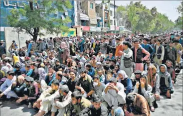  ??  ?? People sit along a road outside a bank waiting to withdraw money in Shar-e-naw neighbourh­ood, Kabul.