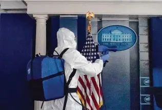  ?? Alex Brandon / Associated Press ?? A member of the cleaning staff on Monday sprays the James Brady Briefing Room of the White House, where the president, first lady and aides have tested positive for the coronaviru­s.