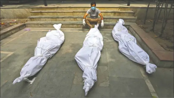  ??  ?? A man waits for the cremation of a relative who died of covid-19, placed near bodies of other victims in New Delhi, India.
