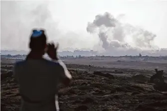  ?? Leo Correa/Associated Press ?? A person in Sderot in southern Israel watches smoke after an explosion in the Gaza Strip on Monday during Israel’s annual Memorial Day for fallen soldiers.