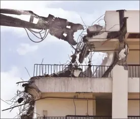  ??  ?? An equipment operator from Northwest Demolition &amp; Dismantlin­g uses a high-reach excavator and hydraulic processor Thursday afternoon to methodical­ly bring down a section of the old hotel