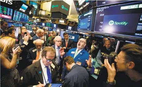  ?? Michael Nagle / Bloomberg ?? Traders work on the floor of the New York Stock Exchange on the first day of trading for the Spotify streaming music service.