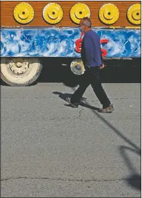  ??  ?? Stelios Kolonas walks next to a carnival float parked outside a warehouse.