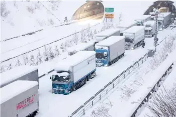  ?? AFP ?? Trucks are seen stuck due to heavy snow on the Shin-meishin Expressway in Yokkaichi, Mie Prefecture, on Wednesday. —