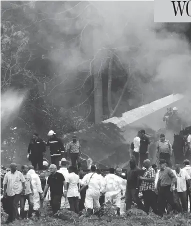  ?? ENRIQUE DE LA OSA / THE ASSOCIATED PRESS ?? Cuba’s President Miguel Diaz-Canel, third from left, walks away from the site where a Boeing 737 plummeted into a field with more than 100 passengers on board, in Havana, Cuba, on Friday. It crashed shortly after takeoff.