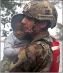  ?? The Associated Press ?? Rescue team member Sgt. Nick Muhar, from the North Carolina National Guard 1/120th battalion, evacuates a young child as the rising floodwater­s from Hurricane Florence threatened his home in New Bern, N.C., on Friday.