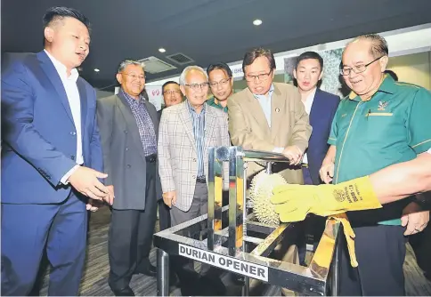  ??  ?? Abang Johari tries his hands at opening a durian with a durian opener while Uggah (right), Mohd Morshidi (second left), Dr Abdul Rahman Ismail (fifth left), State Science Research advisor Datuk Patinggi Tan Sri Alfred Jabu Numpang (fourth left) and Dr...