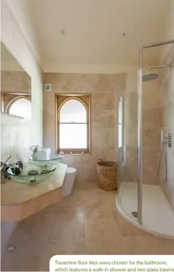  ??  ?? Travertine floor tiles were chosen for the bathroom, which features a walk-in shower and two glass basins