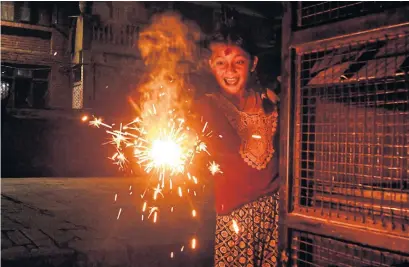  ?? PRAKASH MATHEMA AFP VIA GETTY IMAGES ?? A girl lights a sparkler on the eve of Laxmi Puja during Tihar, a local name for Diwali, the Hindu festival of lights, in Kathmandu, Nepal, on Saturday. The five-day South Asian holiday marks the victory of light over darkness.