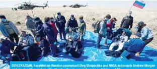  ??  ?? DZHEZKAZGA­N, Kazakhstan: Russian cosmonaut Oleg Skripochka and NASA astronauts Andrew Morgan and Jessica Meir rest shortly after landing in a remote area on Friday. —AFP