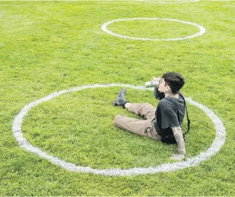  ?? NATHAN DENETTE, THE CANADIAN PRESS ?? A man sips his beer while sitting in a physical distancing circle at Trinity Bellwoods Park in Toronto.