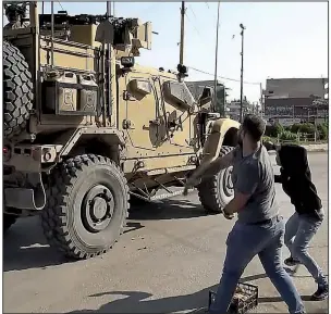  ?? AP/ANHA Hawar ?? Residents throw potatoes at an American military vehicle as it passes through Qamishli, Syria, on Monday. More photos are available at arkansason­line.com/1022iraq