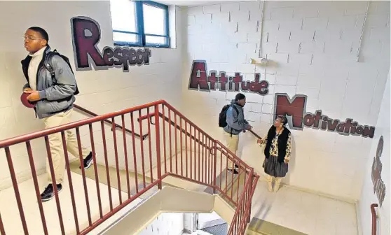  ?? AMY DAVIS/BALTIMORE SUN ?? Daivon Belt, left, heads to class at Silver Oak Academy as another student talks with GED teacher Sheila Leatherbur­y, who was monitoring the stairwell during class change.