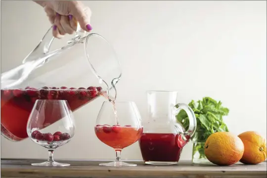  ?? PHOTOS BY CHEYENNE COHEN — KATIE WORKMAN ?? Leftover champagne is poured to add a bit of sparkle to this Cranberry Orange Shrub.